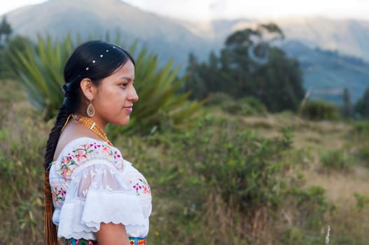 copy-space of an indigenous girl from ecuador in indigenous clothing looking in profile to the camera, the girl is in the mountains. Hispanic Heritage Month. High quality photo