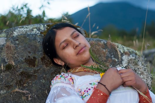 pretty young indigenous girl relaxing with her eyes closed in the middle of nature in a traditional white dress from Ecuador.Hispanic Heritage month. High quality photo