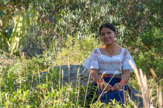 copy-space of a young indigenous girl from Ecuador sitting amidst lush nature looking at the camera and smiling.Hispanic Heritage Month. High quality photo