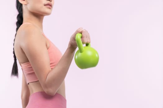 Vigorous energetic woman doing kettlebell weight lifting exercise on isolated background. Young athletic asian woman strength and endurance training session as body workout routine.