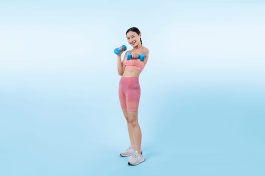 Vigorous energetic woman doing dumbbell weight lifting exercise on isolated background. Young athletic asian woman strength and endurance training session as body workout routine.