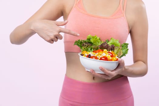 Young sporty Asian woman in sportswear holding salad bowl fill with vibrant of fruit and vegetable. Natural youthful and fit body lifestyle with balance nutrition on isolated background. Vigorous