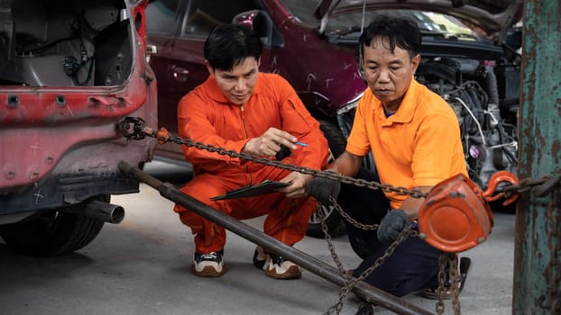 Mechanic testing strength and reliability of chain hoist for car towing in car workshop garage. Automotive service worker ensure through inspection of mechanical equipment. Oxus