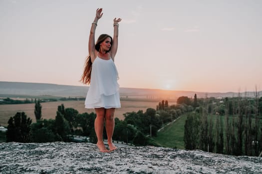 Romantic beautiful bride in white dress posing with sea and mountains in background. Stylish bride standing back on beautiful landscape of sea and mountains on sunset