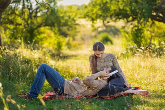 young couple sitting in nature and listening to music with headphones