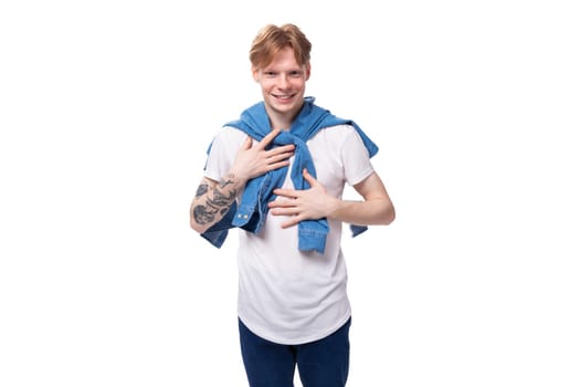 young handsome caucasian man with golden red hair with a tattoo on his arms is dressed in a white t-shirt.