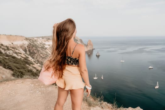 Woman travel sea. Happy tourist taking picture outdoors for memories. Woman traveler looks at the edge of the cliff on the sea bay of mountains, sharing travel adventure journey.