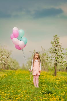 girl with balloons in a young apple orchard