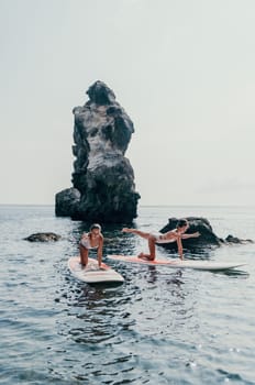 Woman sup yoga. Middle age sporty woman practising yoga pilates on paddle sup surfboard. Female stretching doing workout on sea water. Modern individual hipster outdoor summer sport activity