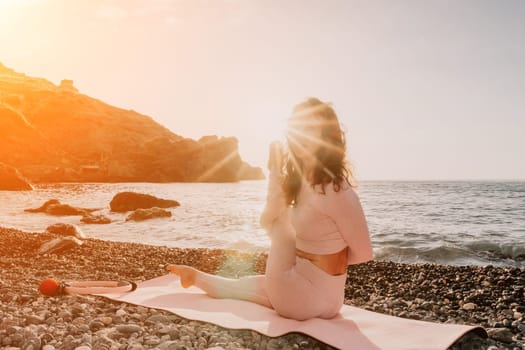 Young woman with black hair, fitness instructor in pink sports leggings and tops, doing pilates on yoga mat with magic pilates ring by the sea on the beach. Female fitness daily yoga concept