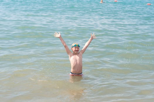 Child playing happily in the sea with hands up, Bright sunlight illuminates the scene, Concept of children's fun and happiness on the beach in Turkey