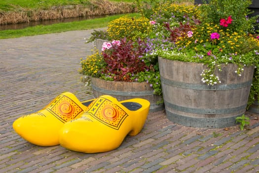 Netherlands. Summer day in Zaanse Schans. Flowers in wooden barrels and giant klompen (Dutch wooden sandals)