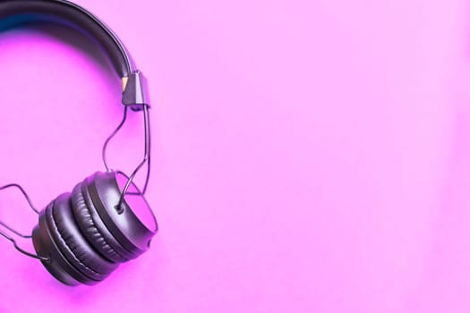 Flat lay concept: Black headphones on pastel colorful pink backgrounds top view.