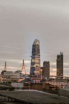Bangkok, Thailand - Aug 14, 2024 - City view with KingBridge tower alongside the iconic landmark of Bhumibol Bridge. Stunning At Twilight skyline of bangkok business district with Skyscrapers use it as your wallpaper, poster and banner design, Selective focus.
