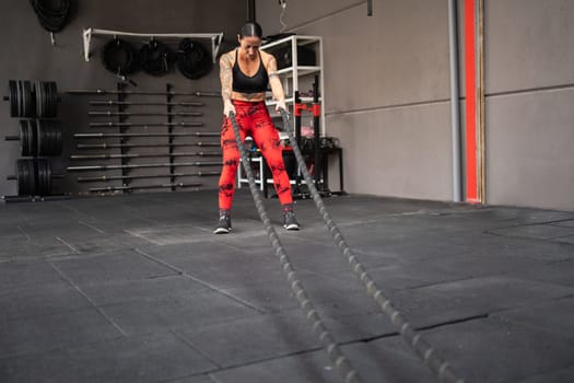 Photo with copy space of a strong woman using battle rope in a gym