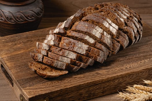 Sliced rye bread on a rustic cutting board and rye ears. High quality photo
