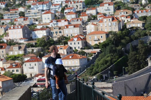 April 22, 2023 Dubrovnik, Croatia, old town, tiled roof of a house ancient stone building with a triangular facade, top view, yang people family tourists walking . High quality photo