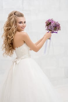 Gorgeous young bride in studio throwing her exquisite pink and violet bouquet