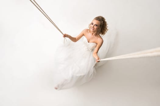 Young beautiful bride with gorgeous hair style posing on a swing shot made from above
