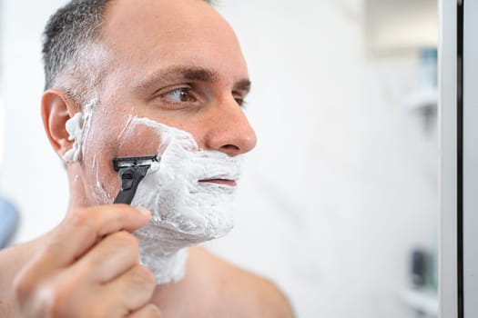 Close up portrait of man in front of shaving mirror in bathroom.