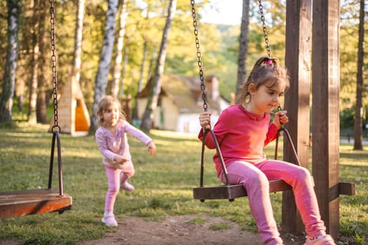 Cute little girl is rocking her older sister on the playground.
