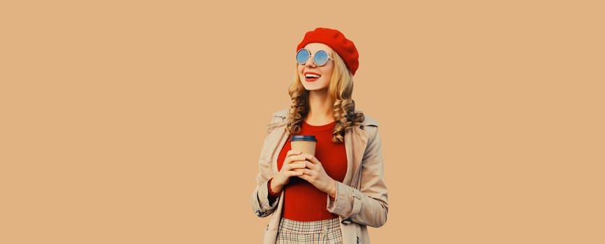 Autumn fashion, portrait of beautiful happy smiling young woman with cup of coffee drink, stylish girl in red french beret hat, coat jacket posing on brown background