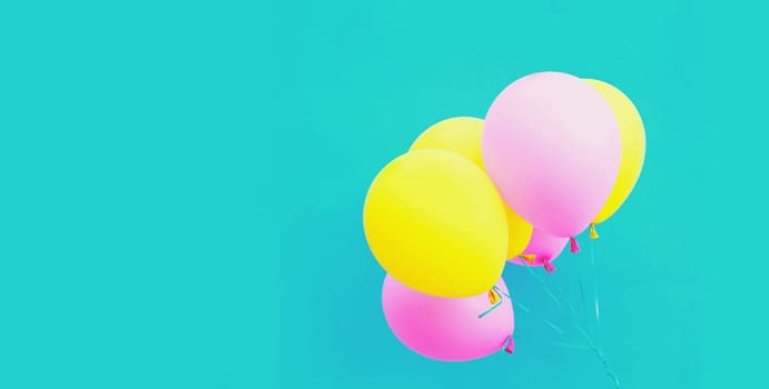 Bunch of festive colorful yellow pink balloons on a blue background