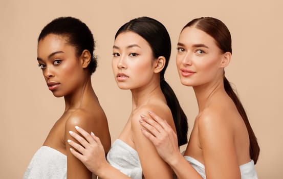 Spa And Beauty Concept. Three Gorgeous Diverse Women In Bath Towels Posing Over Gray Background. Studio Shot