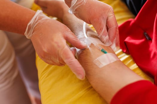 A healthcare professional wearing gloves is preparing to insert an IV into a patient's arm