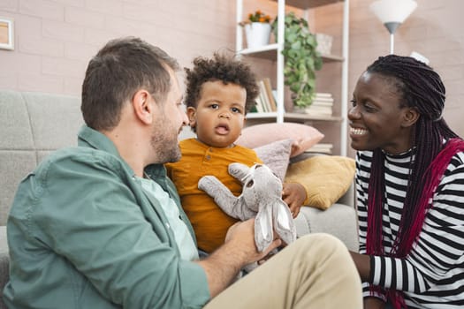 A young family shares laughter while playing with a child indoors.