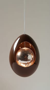 Chocolate egg with disco ball inside on beige background.