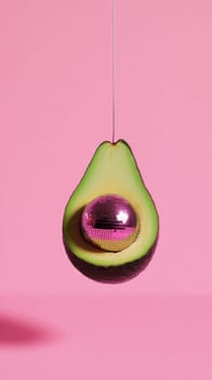 Avocado with disco ball in pink background, creative concept.