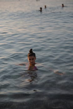 A breathtaking moment of tranquility as a young girl enjoys the serene calm waters during the sunset hour