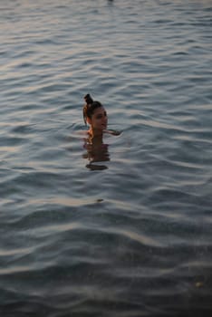 A beautiful and tranquil moment is captured as a woman swims peacefully in the reflective water surface, evoking calm