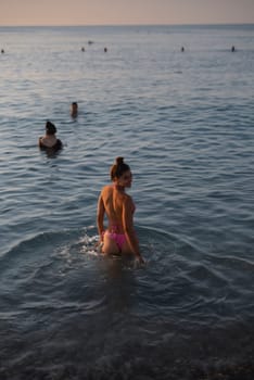 Groups of people are enjoying a peaceful and relaxing evening in the tranquil waters while watching the sunset