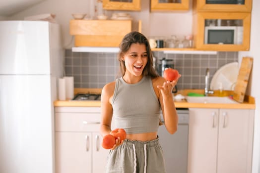 A joyful woman, beaming with happiness, holding fresh tomatoes in a stylish kitchen that exudes healthy living