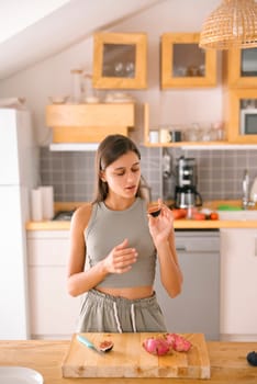 A young woman is scrutinizing fresh produce while passionately cooking in her stylish and modern kitchen