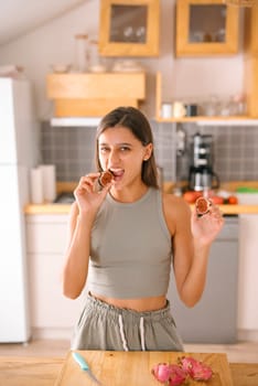 A young woman is enjoying and savoring a delicious snack in a bright, airy, and modern kitchen setting