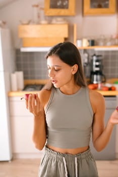 A woman carefully inspects a fresh piece of fruit in her kitchen, emphasizing a vibrant and healthy lifestyle