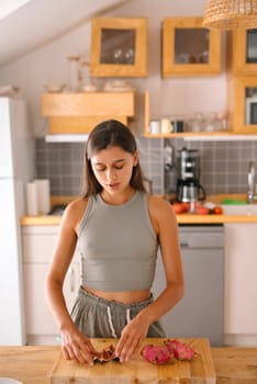 A young woman is preparing a variety of colorful fruits in a stylish and modern kitchen setting with flair