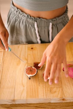 A person skillfully slices a ripe fig on a rustic countertop, showcasing impressive culinary skills