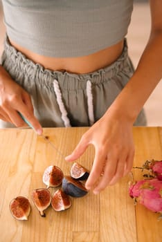 A person delicately handles fresh figs on a rustic wooden table, showcasing exceptional culinary creativity