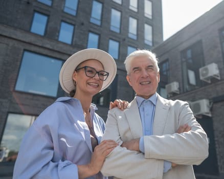 An elderly couple in love walks through the city. Portrait of a stylish gray-haired man and woman