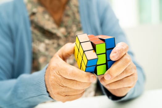 Bangkok, Thailand August 14, 2023 Alzheimer disease AD, Asian elderly woman patient playing Rubik cube game to practice brain training for dementia prevention.