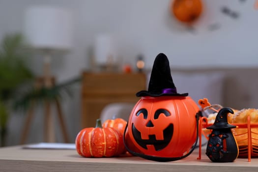 Halloween background with close-up of an orange pumpkin placed on a wooden table in the living room. Festive home decorating ideas.