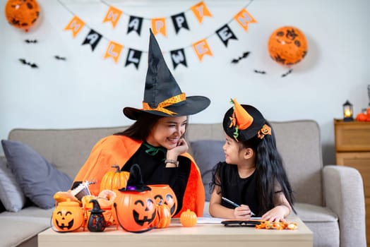 Family mother and daughter prepare decorations for Halloween at home. Draw pictures and cut paper together. and participate in creativity.
