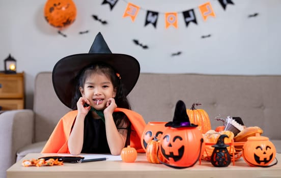 Cute little girl wearing a Halloween costume sits on the sofa with a happy. looking at the camera..