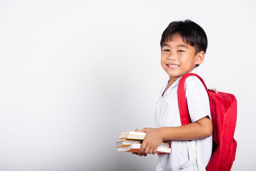 Asian adorable toddler smiling happy wearing student thai uniform red pants stand books for study ready for school isolated on white background, Portrait little children boy preschool, Back to school