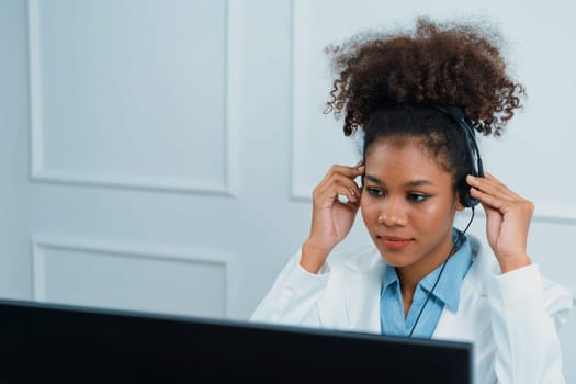 African American businesswoman wearing headset working in office to support remote crucial customer or colleague. Call center, telemarketing, customer support agent provide service on video call.
