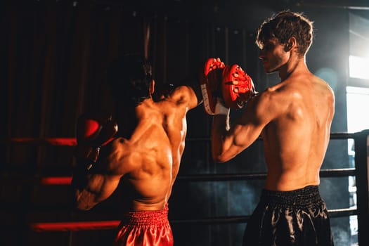 Asian and Caucasian Muay Thai boxer unleash elbow attack in fierce boxing training session, delivering elbow strike to sparring trainer, showcasing boxing technique and skill. Impetus